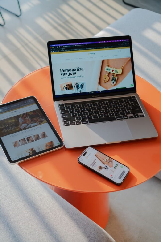 A laptop, tablet, and smartphone displaying websites on an orange table.
